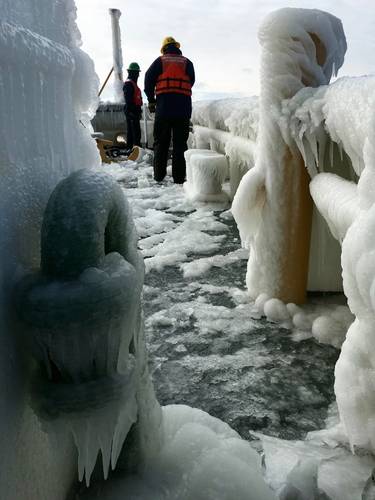Crew members aboard Coast Guard Cutter Neah Bay, work to free the anchor chain of ice buildup on the cutter's bow during training on Lake Erie, January 2016. The crew was running through final drills in preparation for Operation Coal Shovel. (U.S. Coast Guard photo by James Becker)