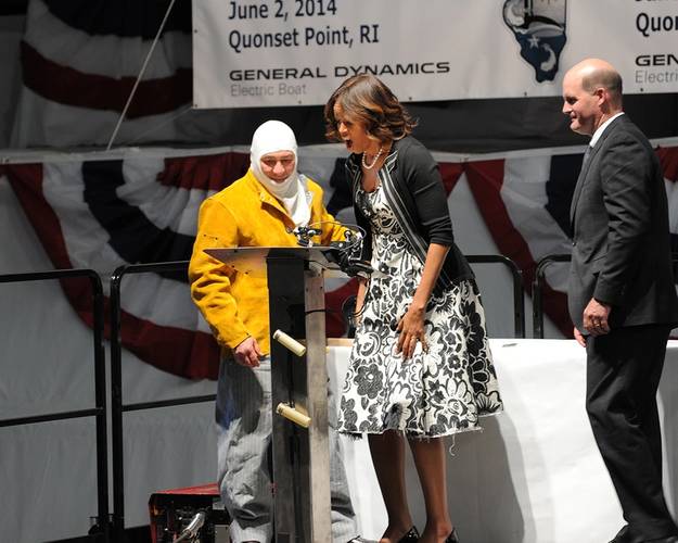 First Lady Michelle Obama reacts enthusiastically to the sight of her initials welded to a steel plate by welder Michael Macomber. The steel plate is now affixed permanently in the submarine. (Photo: General Dynamics Electric Boat)