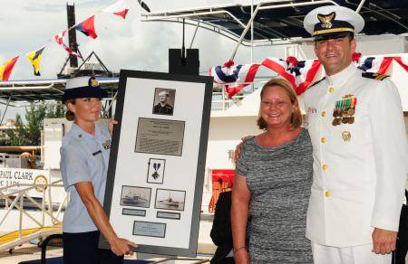 Joanne Kropp, sponsor of Coast Guard Cutter Paul Clark, receives a plaque with the Navy Cross from Lt. W.W. Lloyd Belcher, commanding officer of Paul Clark, during the cutter’s commissioning ceremony. U.S. Coast Guard photo by Petty Officer 3rd Class Jon-Paul Rios.