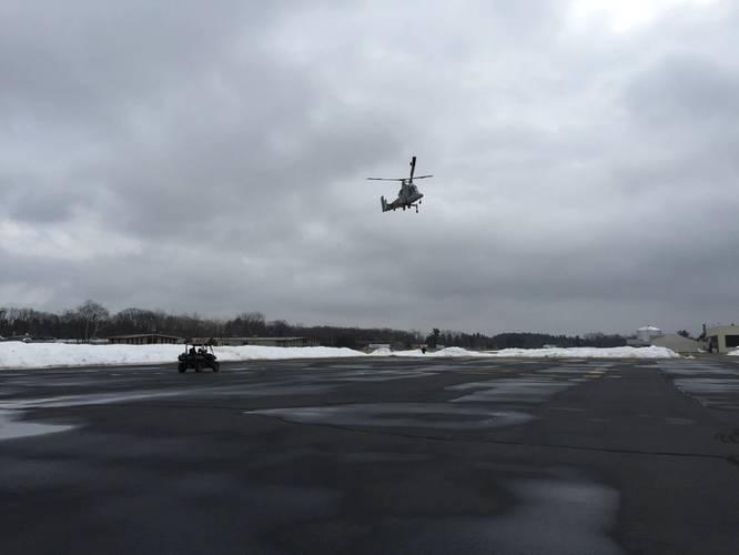 A Kaman K-MAX helicopter flying in the unmanned mode and a Neya Systems UxInterceptor unmanned all-terrain vehicle is controlled by a single operator using a handheld ground control station. (Neya Systems photo)