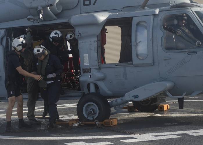 MH-60S crew members assigned to the Blackjacks of Helicopter Sea Combat Squadron 21 escort a Republic of Korea sailor aboard hospital ship USNS Mercy. The Sailor was recovered from Republic of Korea submarine SSK Lee Eok Gi after Mercy received word he was in need of medical attention. (U.S. Marine Corps photo by Brittney Vella)