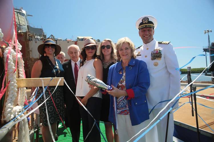 Sally Monsoor, sponsor of the future USS Michael Monsoor (DDG 1001), holds the christening bottle alongside the ship's commanding officer, Capt. Scott Smith; her matrons of honor; and Fred Harris, president of General Dynamics Bath Iron Works (U.S. Navy photo courtesy of Bath Iron Works)