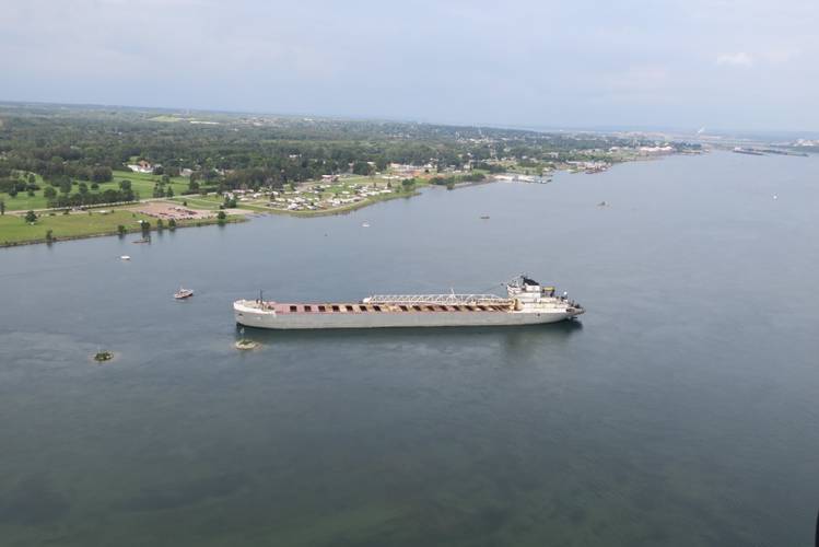 The 629-foot cargo vessel Calumet sits hard aground in the St. Mary's River southeast of Sault Ste. Marie, Michigan, while a Coast Guard response boat - medium encircles the vessel, August 10, 2017. The vessel was heading to its next port of call in Brevort, Michigan when it ran aground. (US Coast Guard photo)